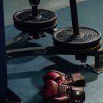 Boxhandschuhe neben Gewichtsscheiben im Gym