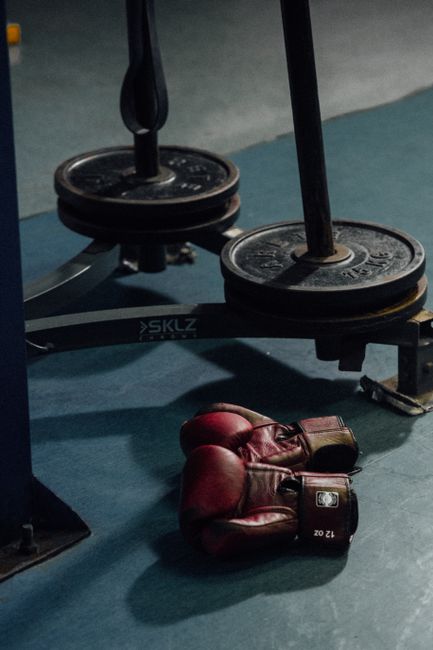 Boxhandschuhe neben Gewichtsscheiben im Gym